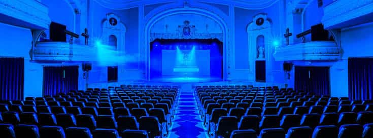 Vista panorámica del interior del teatro con iluminación azul y butacas vacías
