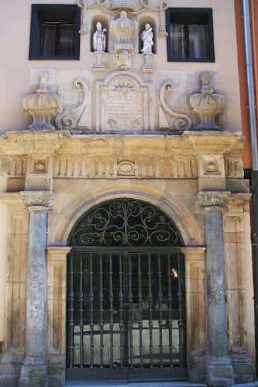 Detalle arquitectónico de una puerta monumental con escultura y reja ornamentada