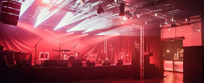 Escenario vacío con iluminación roja y equipo musical listo para el evento