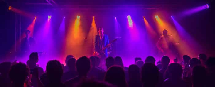 Banda tocando en vivo con luces multicolores y audiencia en primer plano
