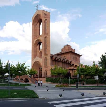 Vista exterior de la Parroquia Santa María de Caná con su distintiva torre de ladrillo bajo un cielo azul