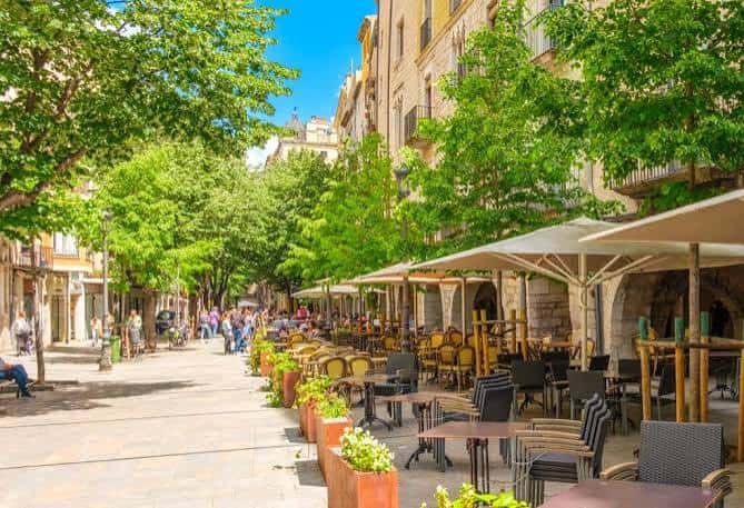 Paseo arbolado en la Rambla de la Llibertat con mesas de cafetería
