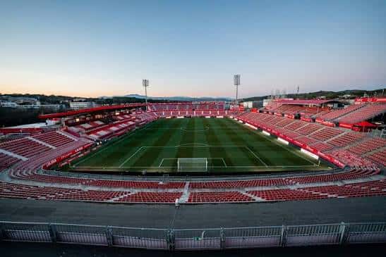 Vista panorámica del interior del Estadi Montilivi con gradas rojas y campo de fútbol