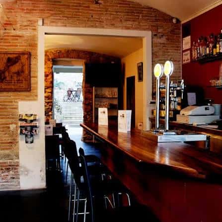 Interior del bar con barra de madera y paredes de ladrillo visto
