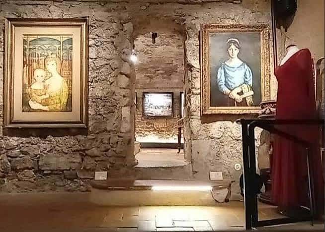 Sala de exposición con cuadros enmarcados y maniquí vestido