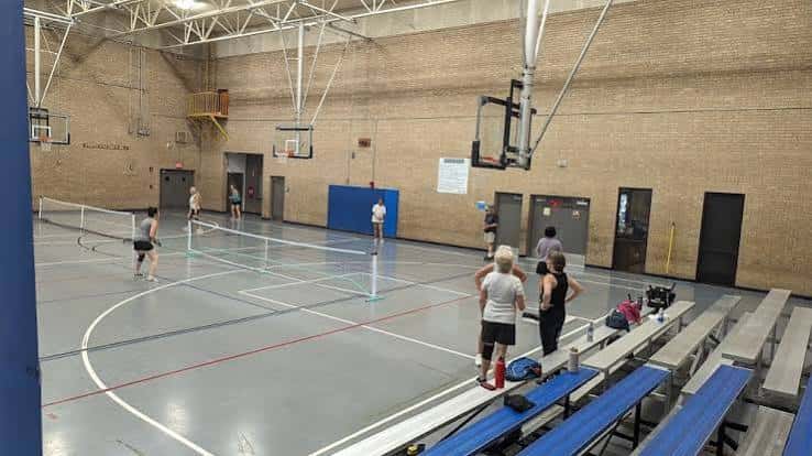 Interior de la cancha polideportiva con personas jugando voleibol