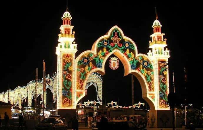 Arco de entrada iluminado con decoración festiva en el recinto ferial