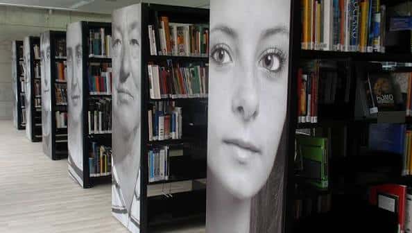 Interior de la biblioteca con estanterías decoradas con retratos en blanco y negro