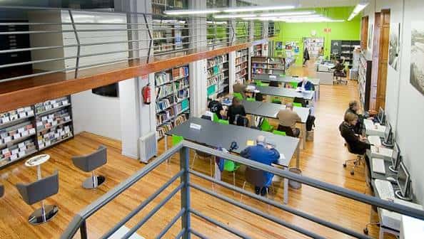 Espacio interior amplio con zonas de lectura, mesas y usuarios trabajando