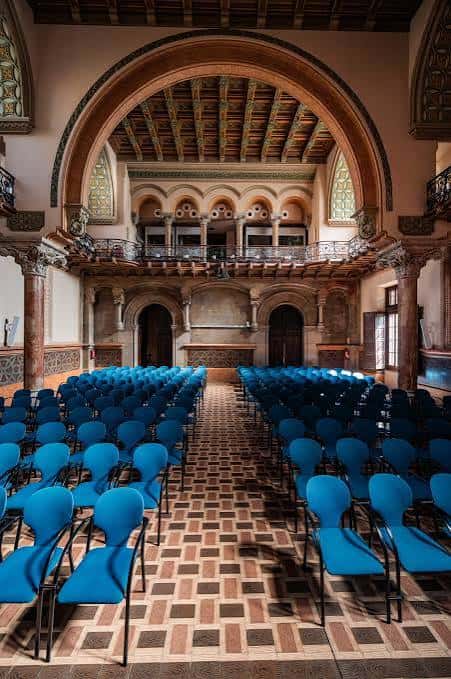 Aula Magna con butacas azules y techo decorado