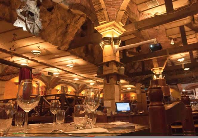Interior del restaurante con techos de piedra y columnas iluminadas