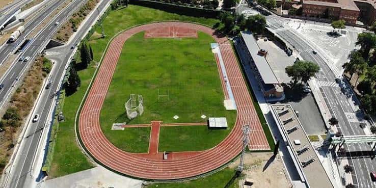 Pista de atletismo con césped central y alrededores urbanos