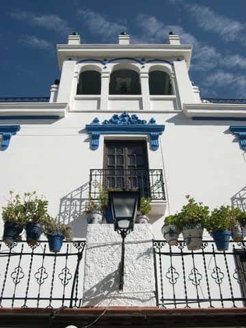 Fachada blanca con detalles azules y balcones de la Peña La Platería