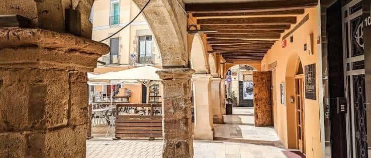 Pasaje cubierto con arcos de piedra y vigas de madera en Igualada