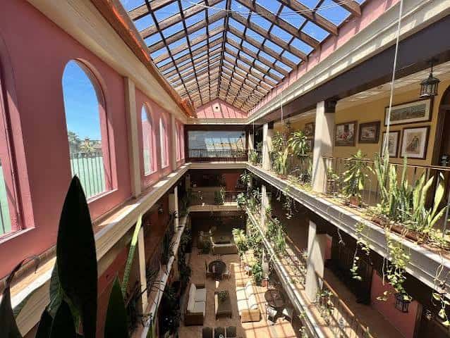 Vista panorámica del atrio interior con techo de cristal y plantas colgantes