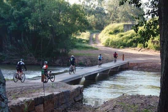 Ciclistas cruzando un puente sobre el río Llobregat en un entorno natural