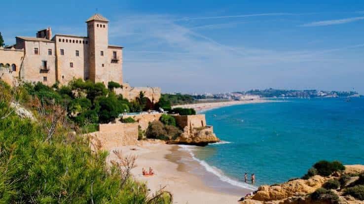 Vista panorámica de Cala Jovera con el Castillo de Tamarit al fondo y aguas turquesas