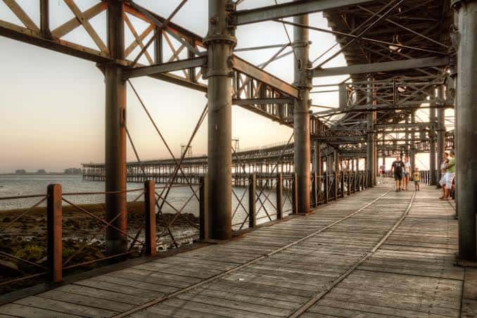 Pasillo interior del muelle con vigas de acero y visitantes caminando