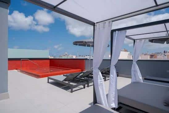Terraza de la piscina con hamacas y toldos blancos
