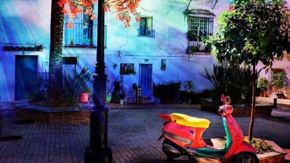 Vista nocturna de la Plaza Juan Antonio Pérez Cervera con iluminación artística y una scooter decorativa