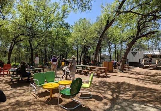Área de picnic en Camp East con árboles y mobiliario colorido