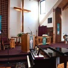 Interior del santuario con altar, cruz de madera y piano