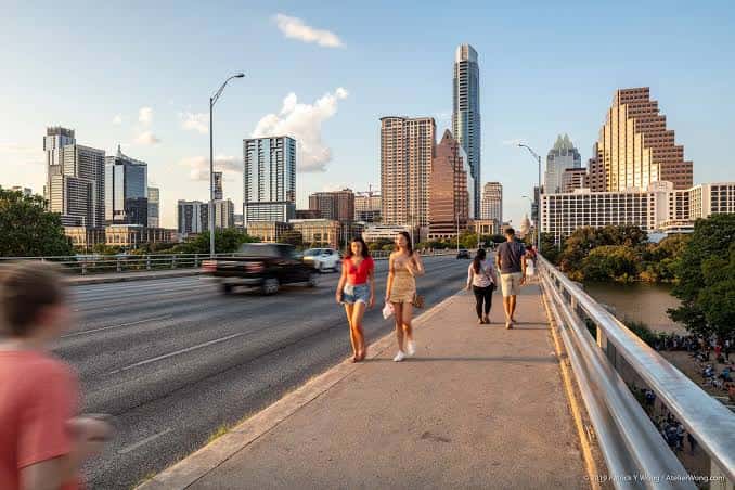 Personas caminando por la acera del puente con el skyline de Austin al fondo