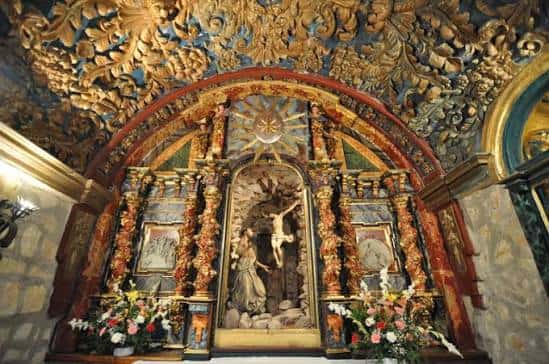 Detalle del altar principal con escultura religiosa y decoración dorada