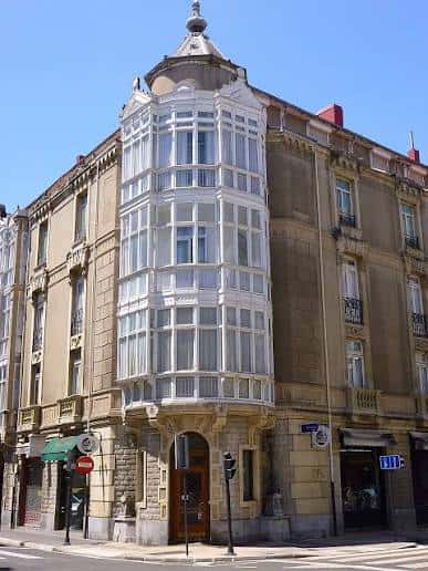 Fachada de un edificio histórico en la esquina de Calle San Antonio con balcón acristalado