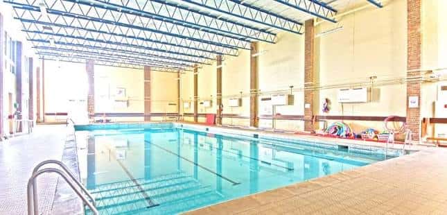 Interior de la piscina cubierta con estructura metálica y columnas de ladrillo