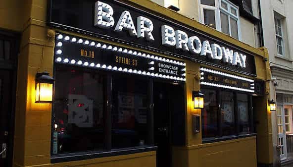 Fachada nocturna del Bar Broadway con letrero luminoso