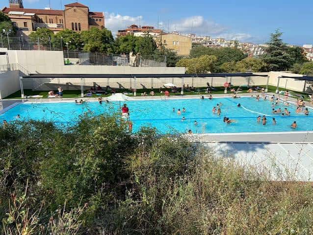 Piscina al aire libre del complejo deportivo con personas nadando y disfrutando del sol