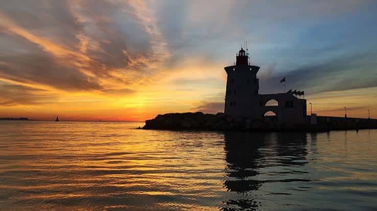 Atardecer en el faro de Puerto Sherry con reflejos dorados en el agua