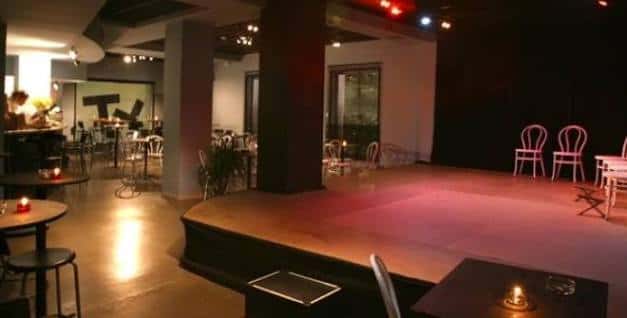 Escenario vacío con sillas blancas y ambiente cálido para espectáculos