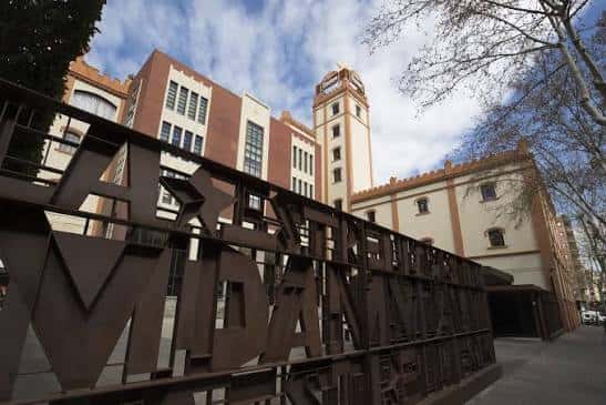 Vista exterior de la Antiga Fàbrica Estrella Damm con el letrero 'MUSEU' en primer plano