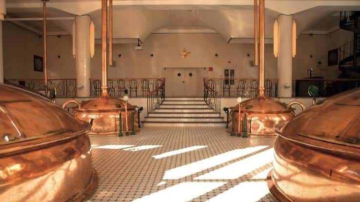 Interior histórico de la fábrica con tanques de cobre y escalinata central