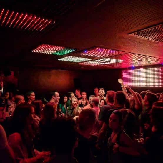 Escena nocturna en el club con iluminación LED y gente bailando