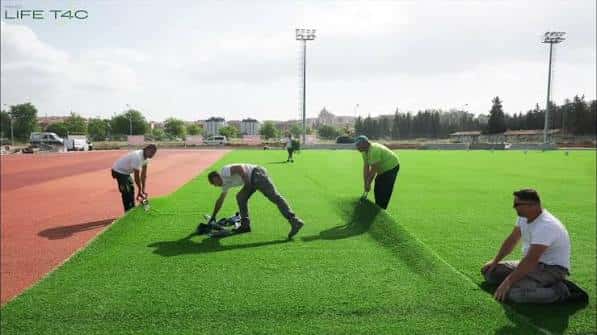 Trabajadores instalando césped artificial en el campo de fútbol