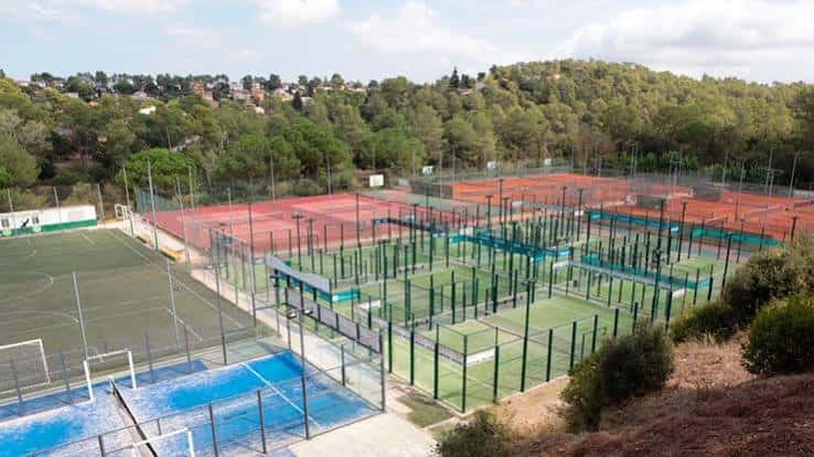 Ampio complejo deportivo con múltiples pistas de pádel y tenis rodeadas de vegetación