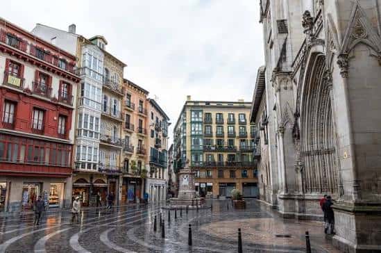 Vista amplia de la plaza con arquitectura tradicional y pavimento mojado reflejando el entorno