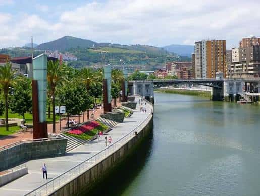 Vista panorámica del paseo marítimo con palmeras y el puente colgante al fondo