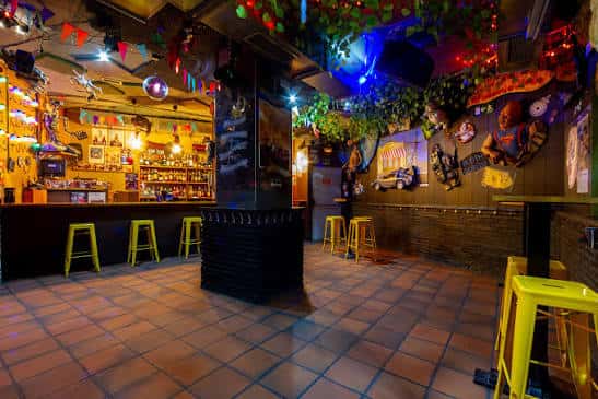 Vista general del interior del bar con decoración temática y barra iluminada