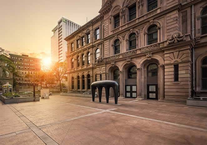 Vista exterior del edificio de la galería al atardecer con una escultura moderna en el patio