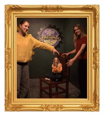 Dos mujeres y un niño posando junto a la silla gigante con el logo del museo