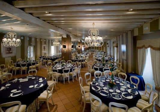 Sala de banquetes interior del Baluarte decorada con mesas redondas y candelabros