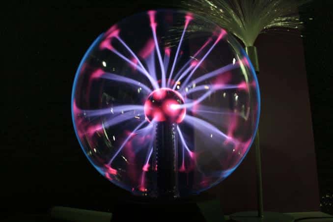 Exhibición interactiva de física con esfera de plasma iluminada en el interior del museo
