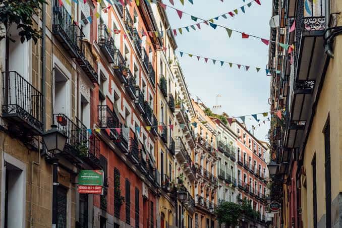 Calle festiva decorada con banderines multicolores entre edificios antiguos