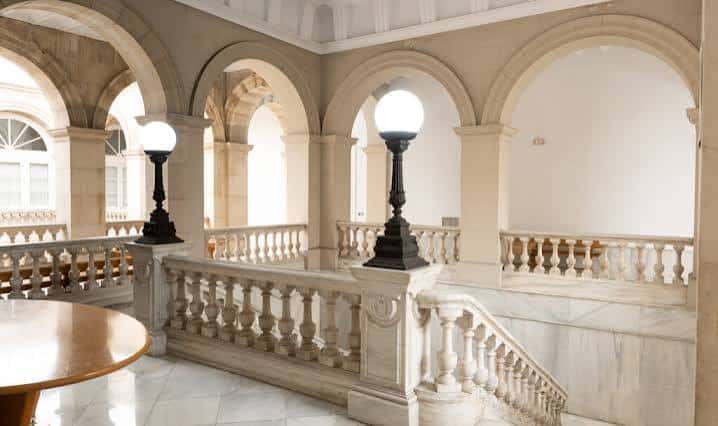 Interior elegante con arcos, escalera de mármol y lámparas clásicas