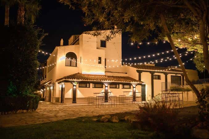 Fachada exterior de Masia Colina iluminada por la noche con luces decorativas
