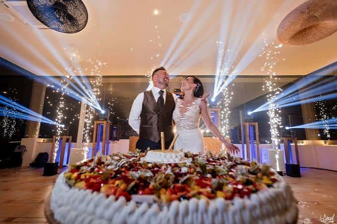 Boda en el interior de Masia Colina con pareja frente a un pastel decorado